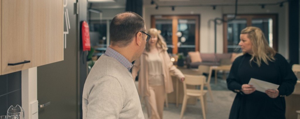 Kolme henkilöä seisomassa toimiston kahvitilassa